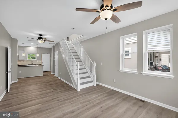 a view of a kitchen with wooden floor a ceiling fan and windows