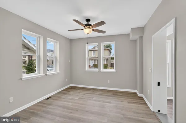 a view of an empty room with a window and wooden floor