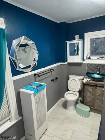 a white toilet sitting next to a bathroom sink and a mirror