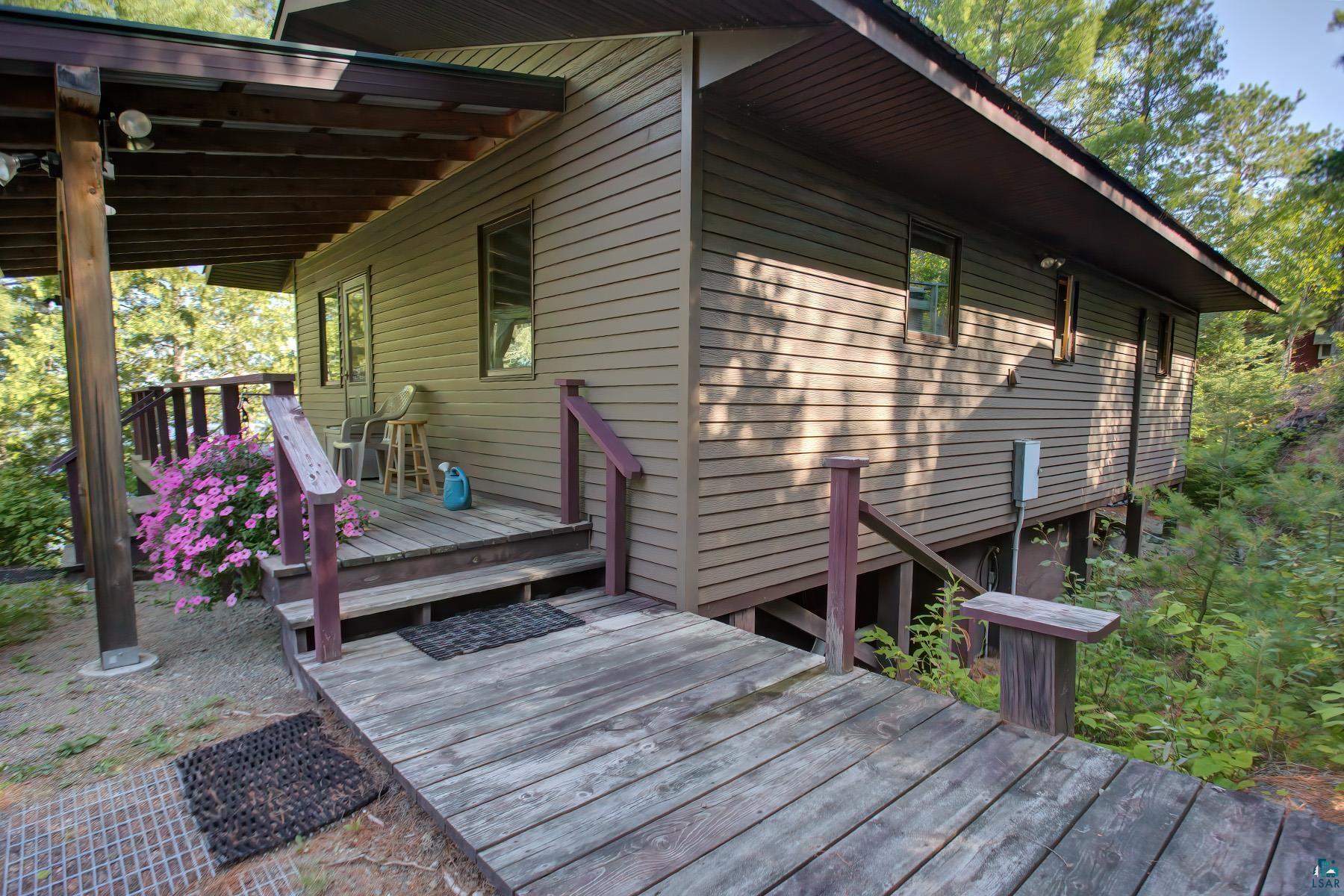 2811 Schaeffer Road Ely, MN 55731 - Photo 2 of 40 Exterior featuring horizontal siding, an extended covered deck, and an accessible wooden ramp entry