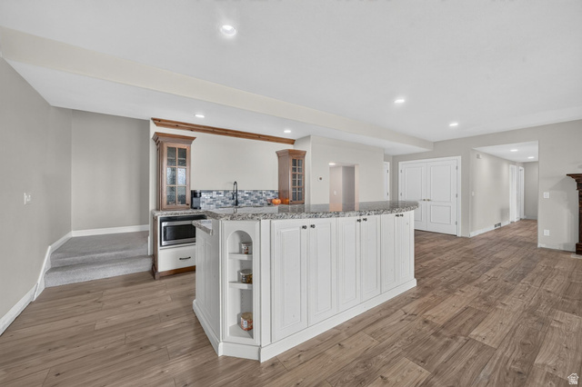 767 Draper View Road Draper, UT 84020 - Photo 36 of 71 Spacious open-concept area featuring wood-finish flooring, a kitchen island with white cabinetry and an integrated sink, recessed lighting, and a built-in microwave