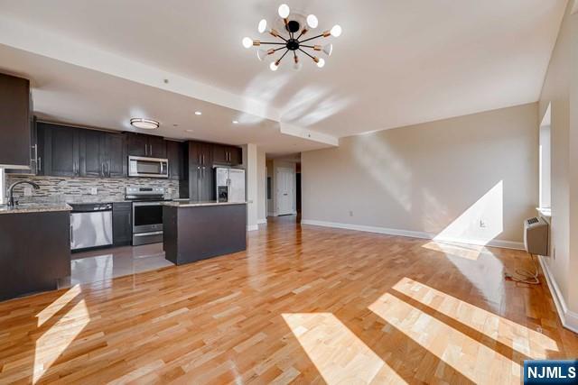 29 1st Street, Unit 401 Hackensack, NJ 07601 - Photo 7 of 26 a view of a kitchen with kitchen island a sink stainless steel appliances and cabinets