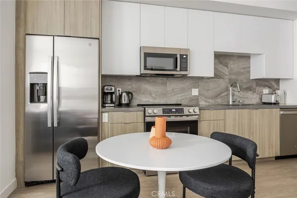 a kitchen with stainless steel appliances granite countertop a dining table chairs and a refrigerator