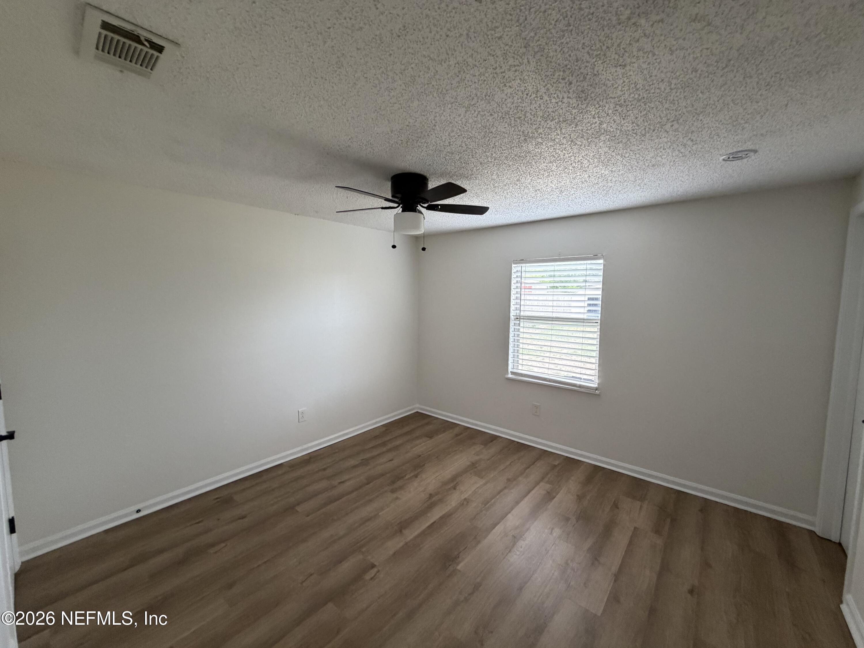 7539 Walden Road Jacksonville, FL 32244 - Photo 11 of 18 an empty room with wooden floor cabinet and windows