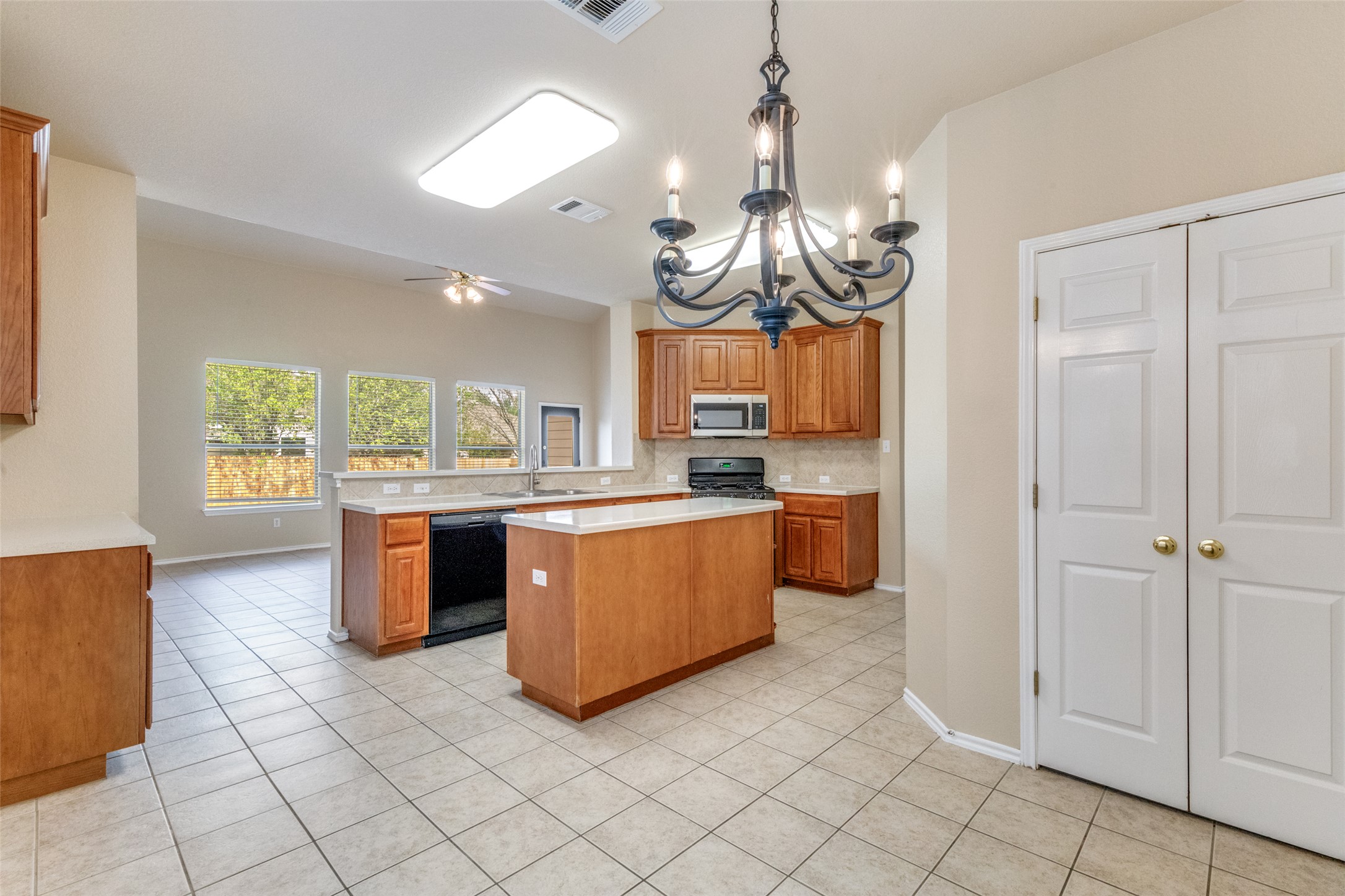 3816 Bandice Lane Pflugerville, TX 78660 - Photo 11 of 33 Kitchen featuring a center island, wood finish cabinetry, light tile patterned floors, black appliances, and ceiling fan