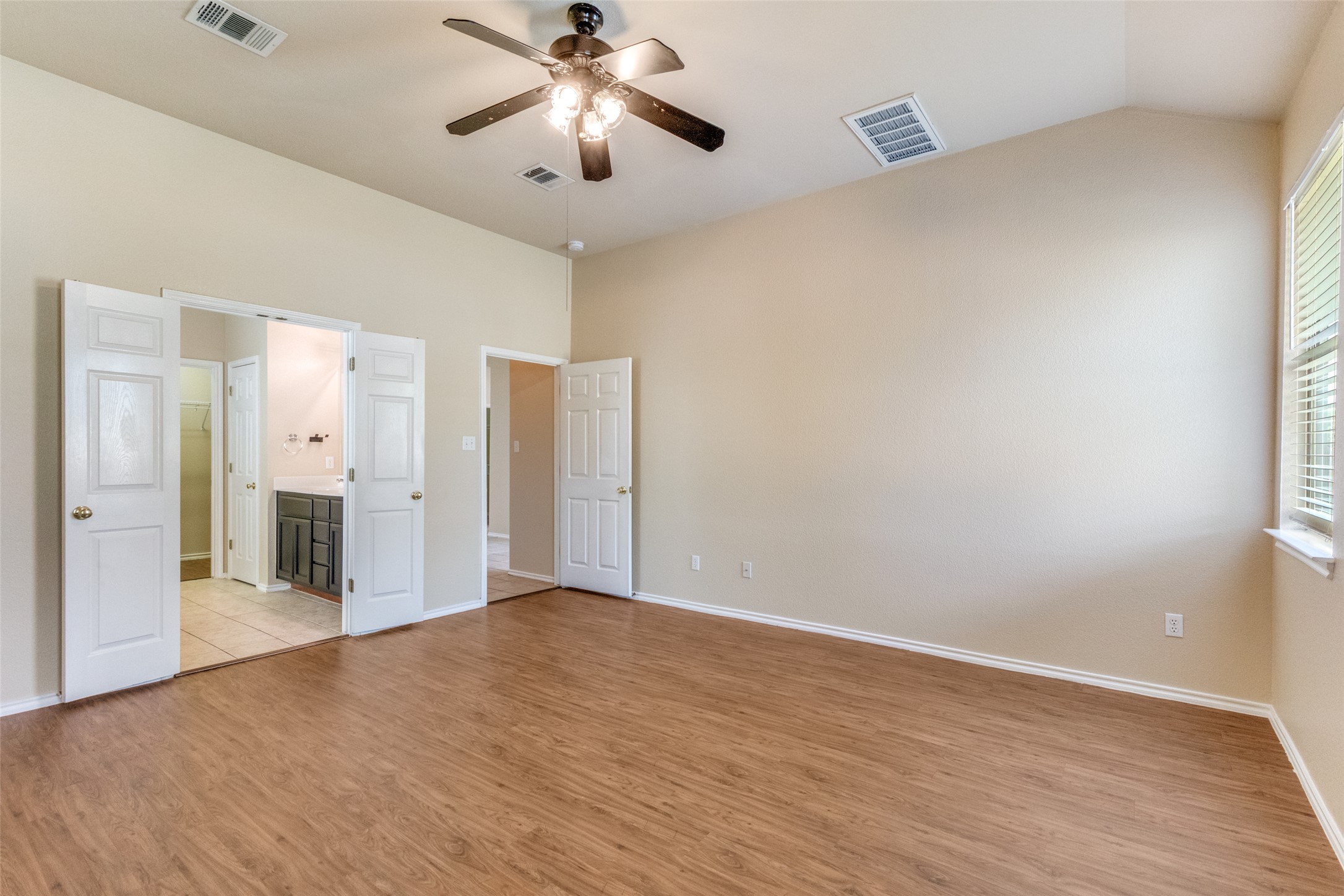3816 Bandice Lane Pflugerville, TX 78660 - Photo 16 of 33 Primary bedroom with light wood finished floors, ensuite bath, lofted ceiling, and ceiling fan