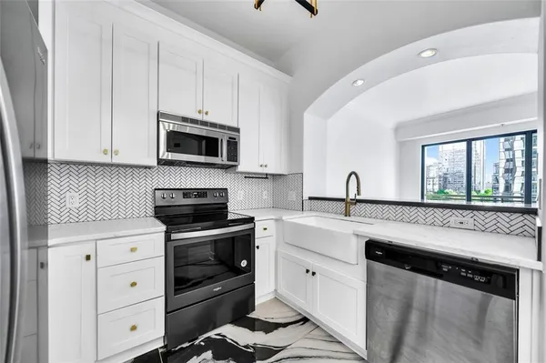 a kitchen with white cabinets and appliances