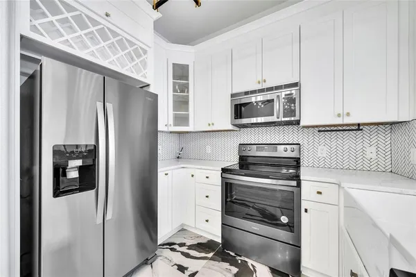 a kitchen with stainless steel appliances white cabinets and a stove a refrigerator with white cabinets