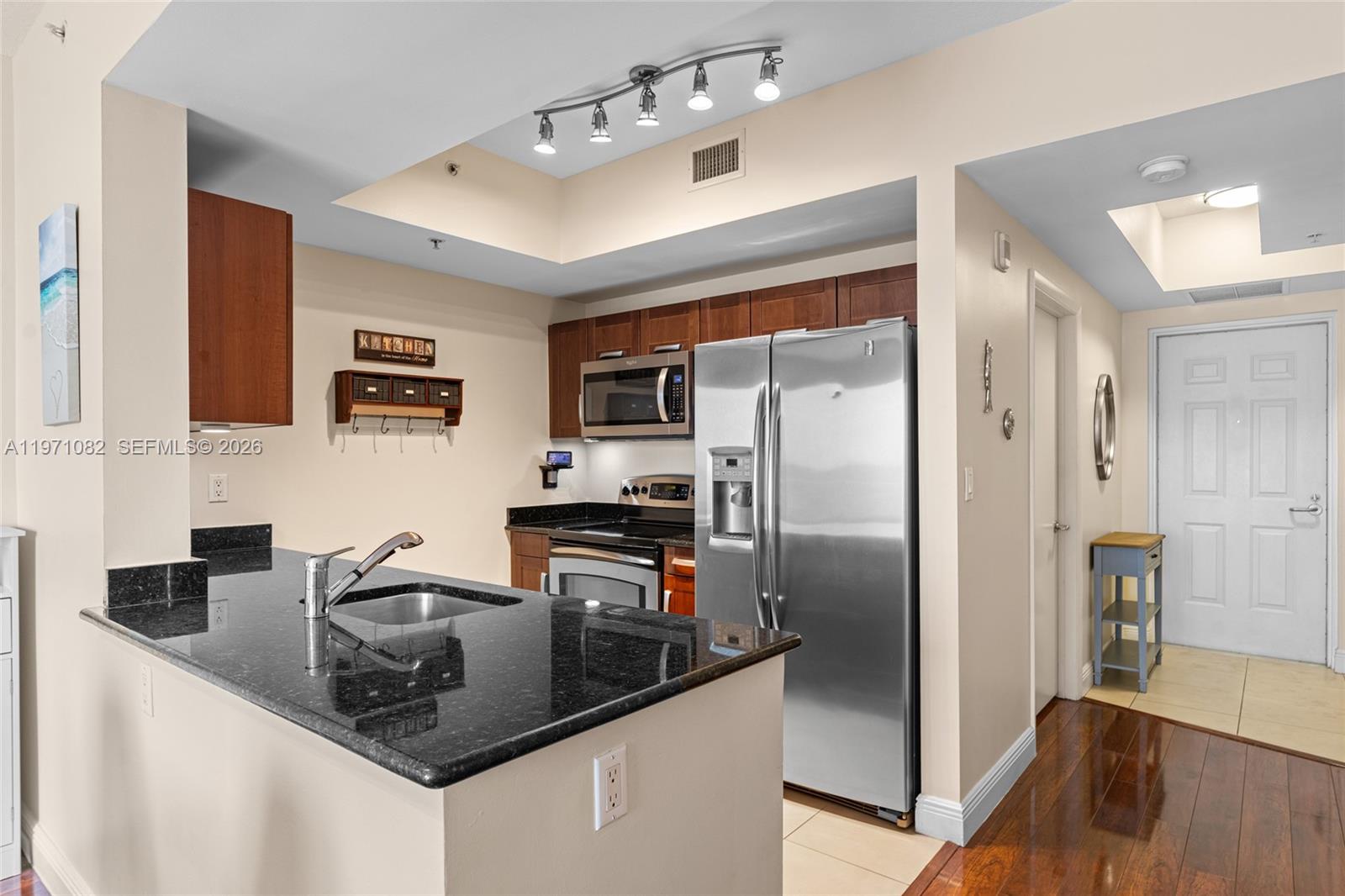 7275 Southwest 90th Way, Unit 404 Miami, FL 33156 - Photo 13 of 35 a kitchen with stainless steel appliances granite countertop a refrigerator a stove and a sink with wooden floor