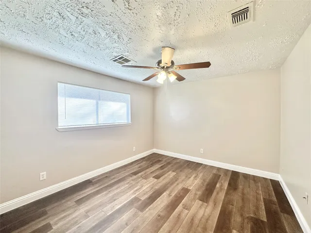 a view of a room with wooden floor and a ceiling fan