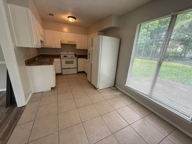 a kitchen with a refrigerator a stove top oven and a large window