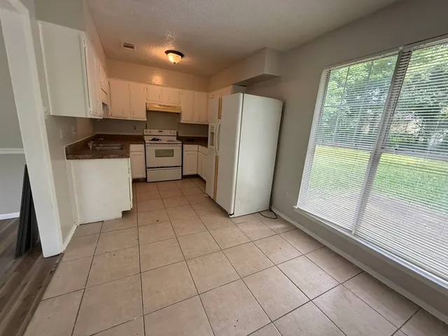 a kitchen with a refrigerator a stove top oven and a large window
