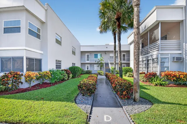 a front view of a house with a yard and potted plants