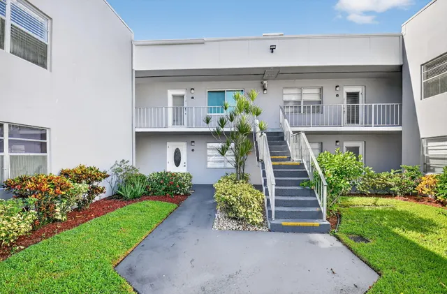 a front view of a house with a yard and potted plants