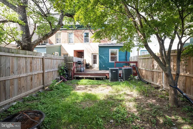 a view of backyard of house with wooden fence and large trees