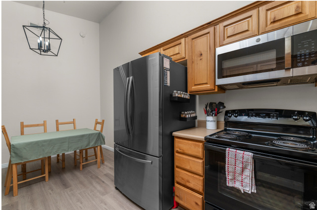 25 West Ridge Road, Unit 25 Saratoga Springs, UT 84045 - Photo 7 of 22 Modern kitchen featuring wood-finish cabinetry, light-toned countertops, and stainless steel appliances including a refrigerator and over-range microwave