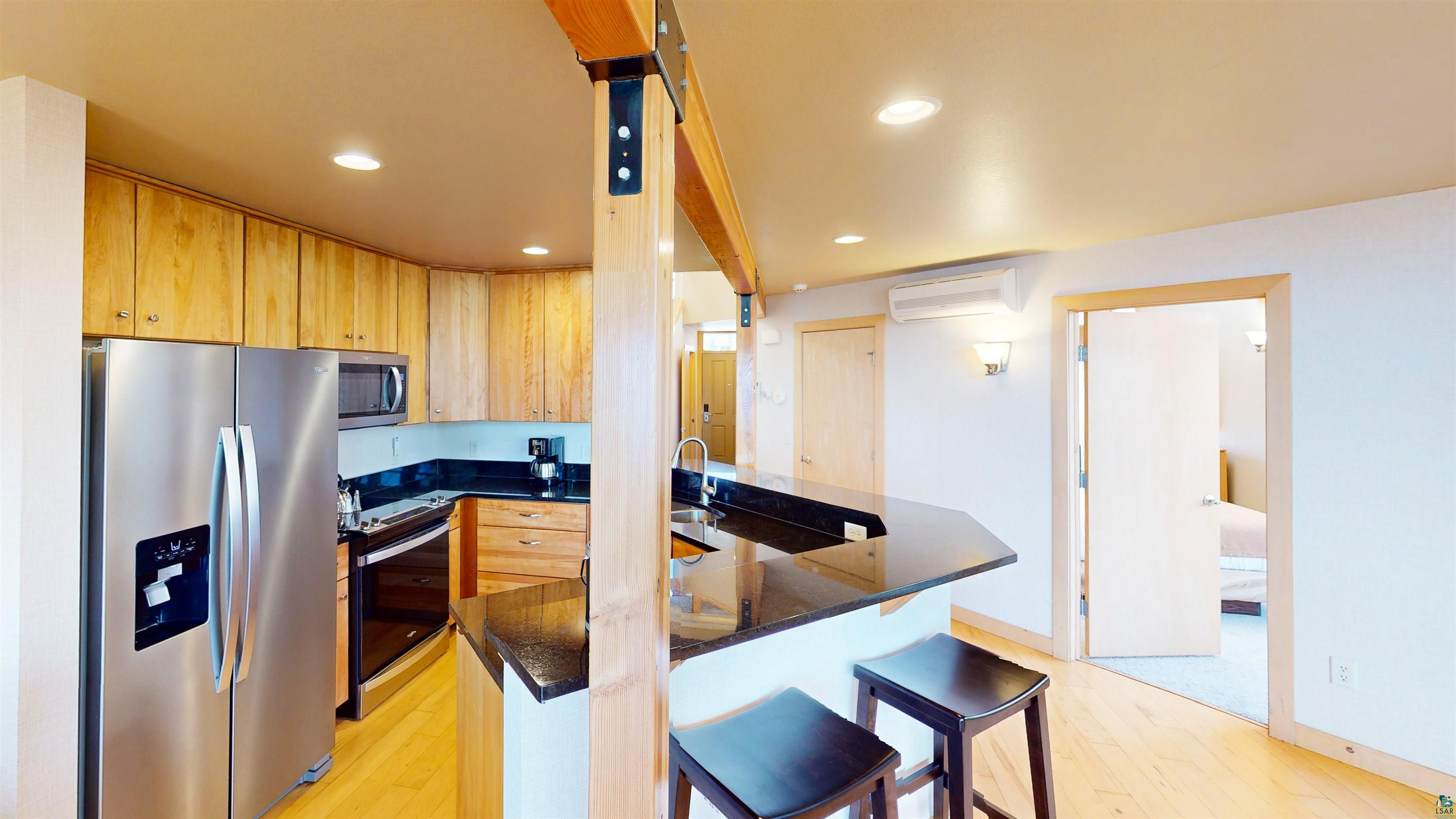 40 Surfside Drive, Unit 5D Tofte, MN 55615 - Photo 9 of 37 Kitchen featuring stainless steel appliances, wood-finish cabinetry, dark countertops, and a breakfast bar with built-in seating