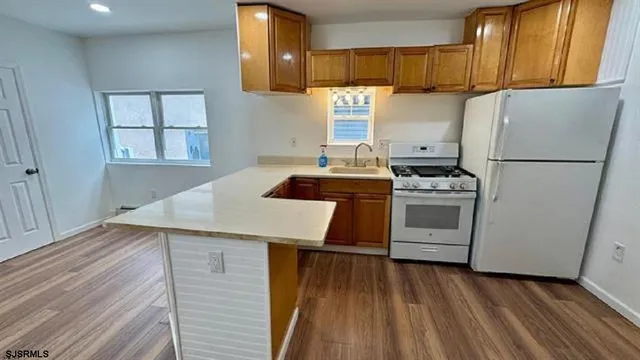 a kitchen with a refrigerator a stove top oven a sink and dishwasher with wooden floor