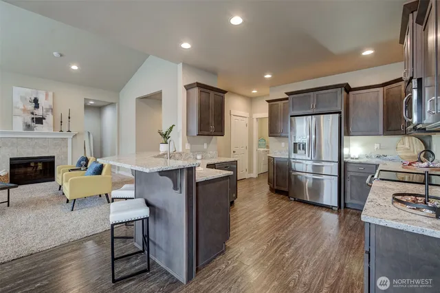 a kitchen with stainless steel appliances a refrigerator a stove a sink dishwasher and microwave with wooden floor