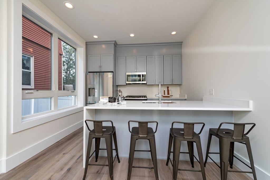116 School Street, Unit 2 Boston, MA 02119 - Photo 5 of 24 a kitchen with granite countertop white cabinets and stainless steel appliances