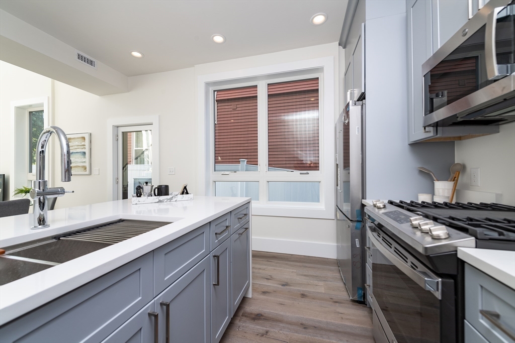 116 School Street, Unit 2 Boston, MA 02119 - Photo 7 of 24 a kitchen with stainless steel appliances granite countertop a sink stove and cabinets