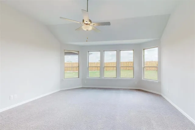 an empty room with chandelier fan and windows