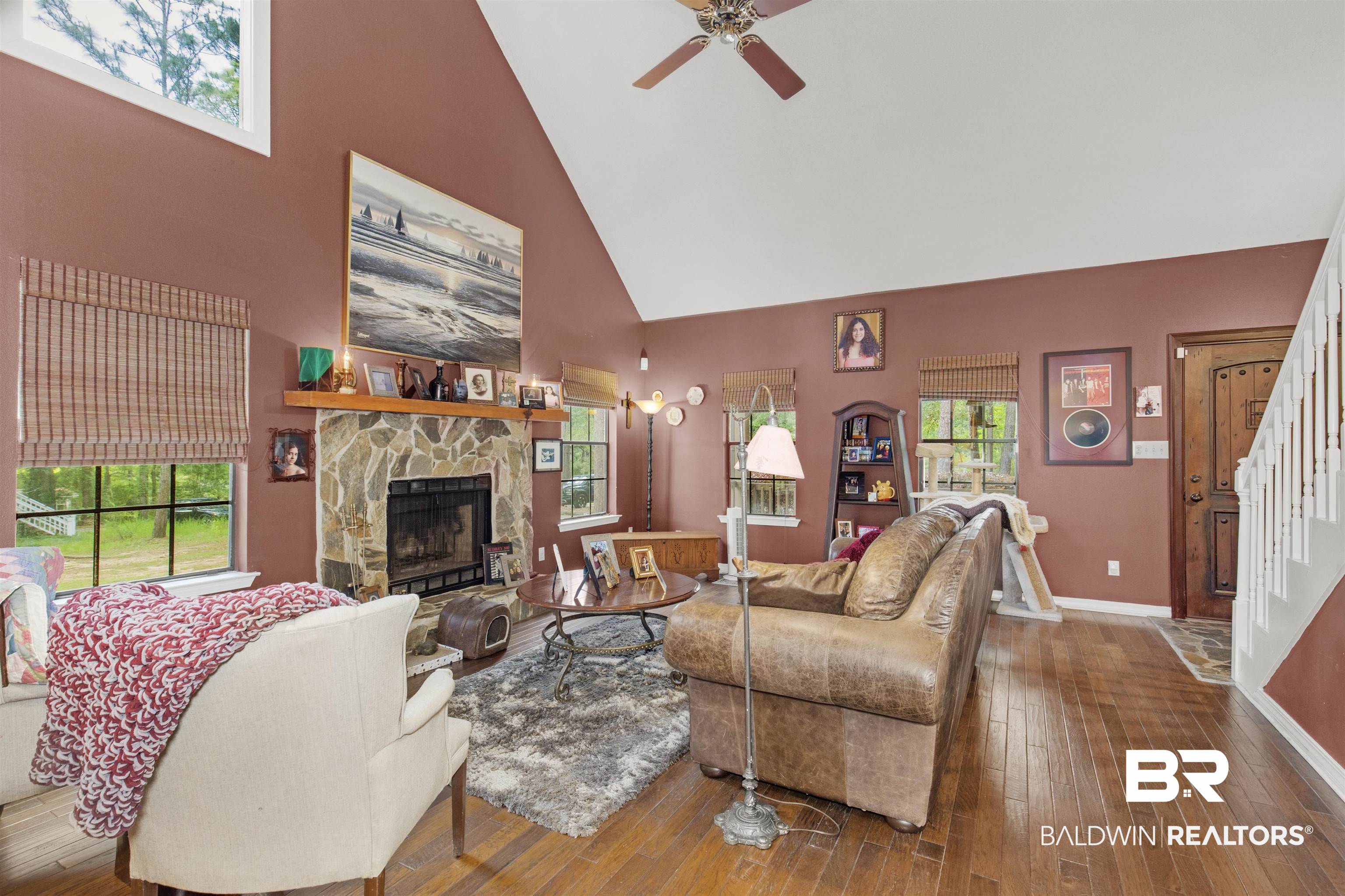 31375 Stagecoach Road Daphne, AL 36527 - Photo 5 of 21 Living room with high vaulted ceiling, a ceiling fan, a stone fireplace, stairs, and wood-type flooring
