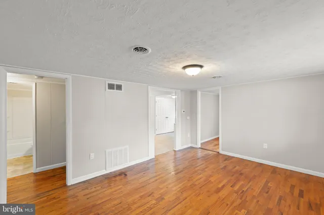 a view of an empty room with wooden floor and closet