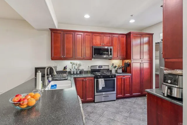 a kitchen with stainless steel appliances granite countertop a stove top oven a sink dishwasher a dining table and chairs with wooden floor