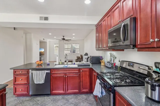 a kitchen with stainless steel appliances granite countertop a stove top oven a sink dishwasher and cabinets with wooden floor