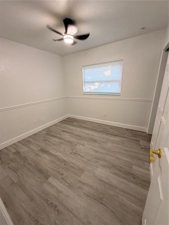 7513 Rustic Drive Tampa, FL 33634 - Photo 12 of 21 an empty room with wooden floor fan and windows