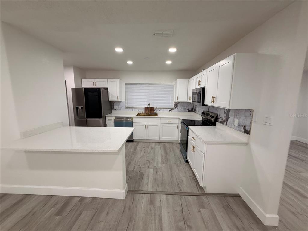 7513 Rustic Drive Tampa, FL 33634 - Photo 18 of 21 a kitchen with a refrigerator a stove top oven and white cabinets