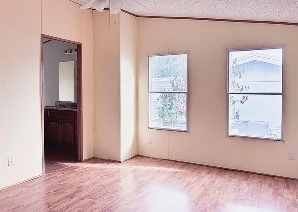 a view of an empty room with a ceiling fan and wooden floor