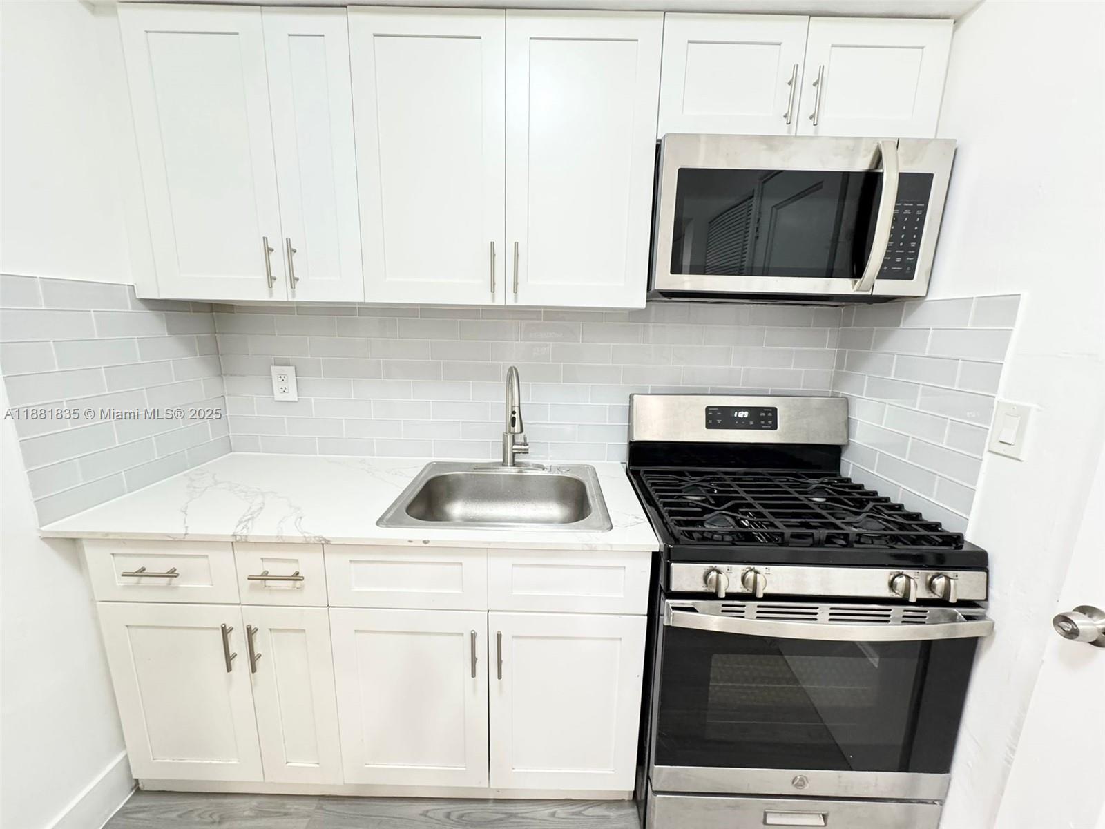 7435 Byron Avenue, Unit 2 Miami Beach, FL 33141 - Photo 1 of 35 a kitchen with stainless steel appliances granite countertop white cabinets a stove top oven