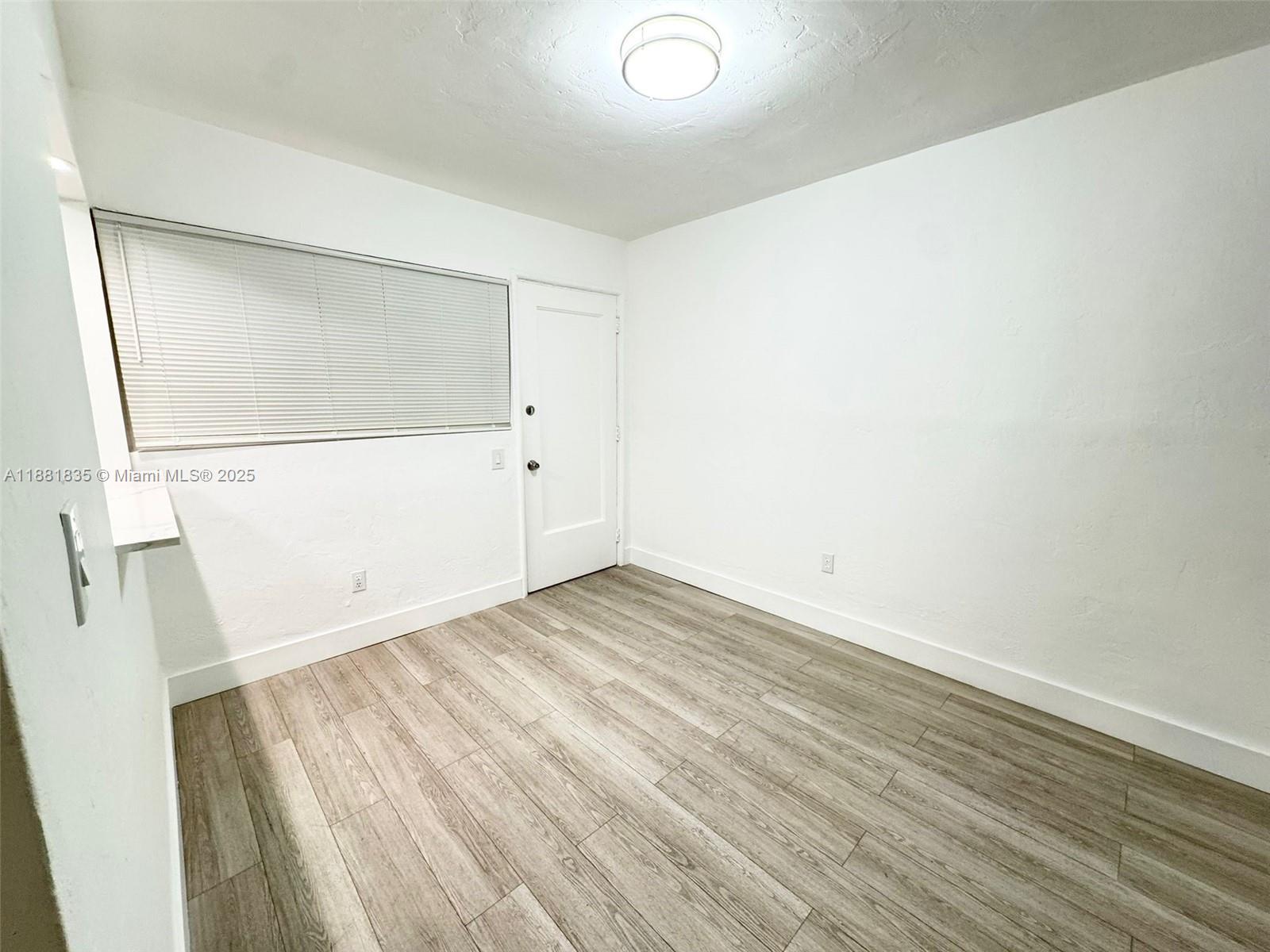 7435 Byron Avenue, Unit 2 Miami Beach, FL 33141 - Photo 16 of 35 an empty room with wooden floor and white walls