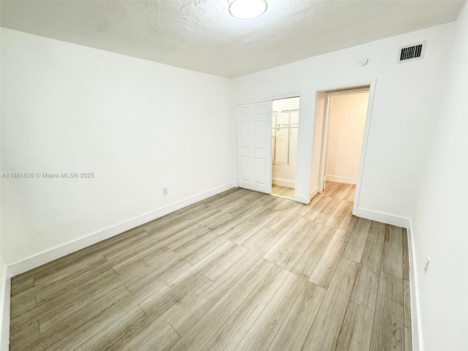 7435 Byron Avenue, Unit 2 Miami Beach, FL 33141 - Photo 17 of 35 an empty room with wooden floor and windows