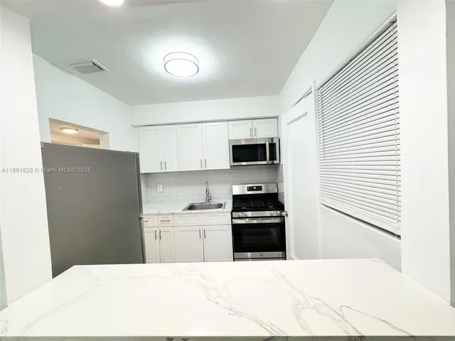 a kitchen with stainless steel appliances kitchen island sink refrigerator and stove