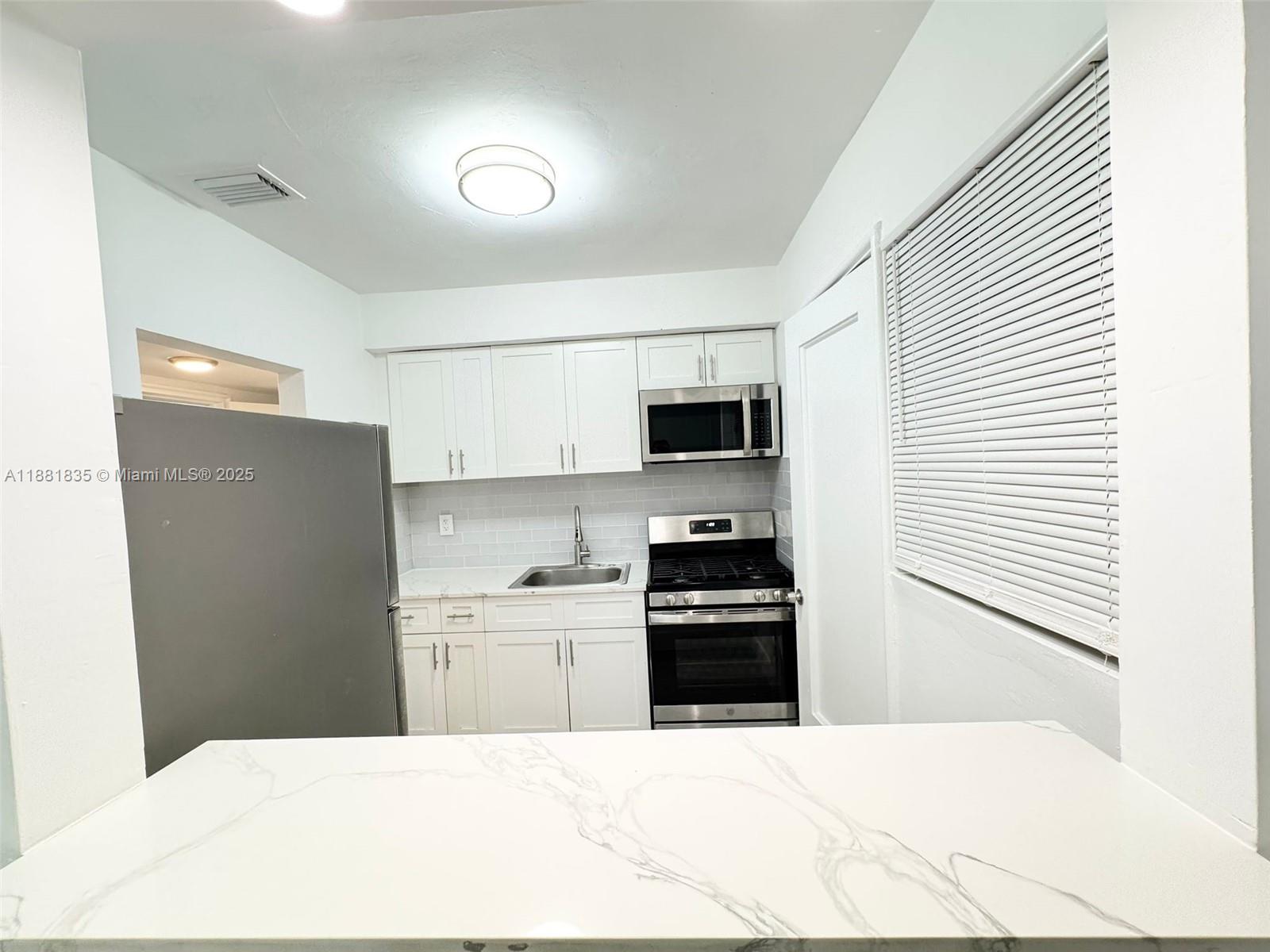 7435 Byron Avenue, Unit 2 Miami Beach, FL 33141 - Photo 2 of 35 a kitchen with stainless steel appliances kitchen island sink refrigerator and stove