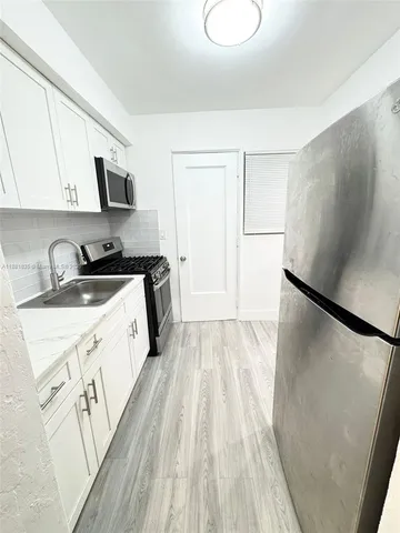 a kitchen with stainless steel appliances a refrigerator sink and white cabinets