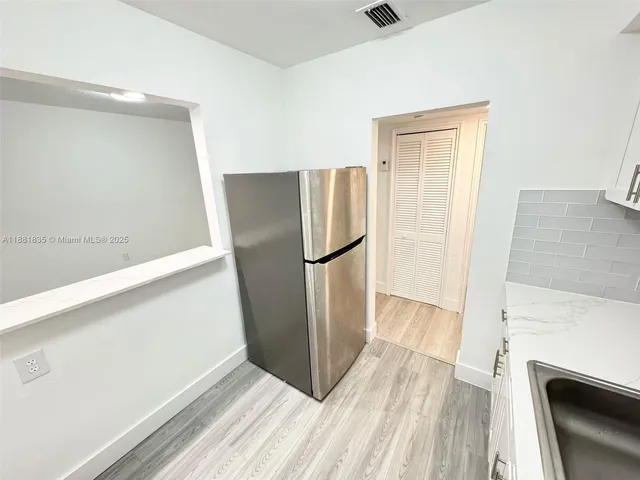 a view of a kitchen with refrigerator stove and wooden floor