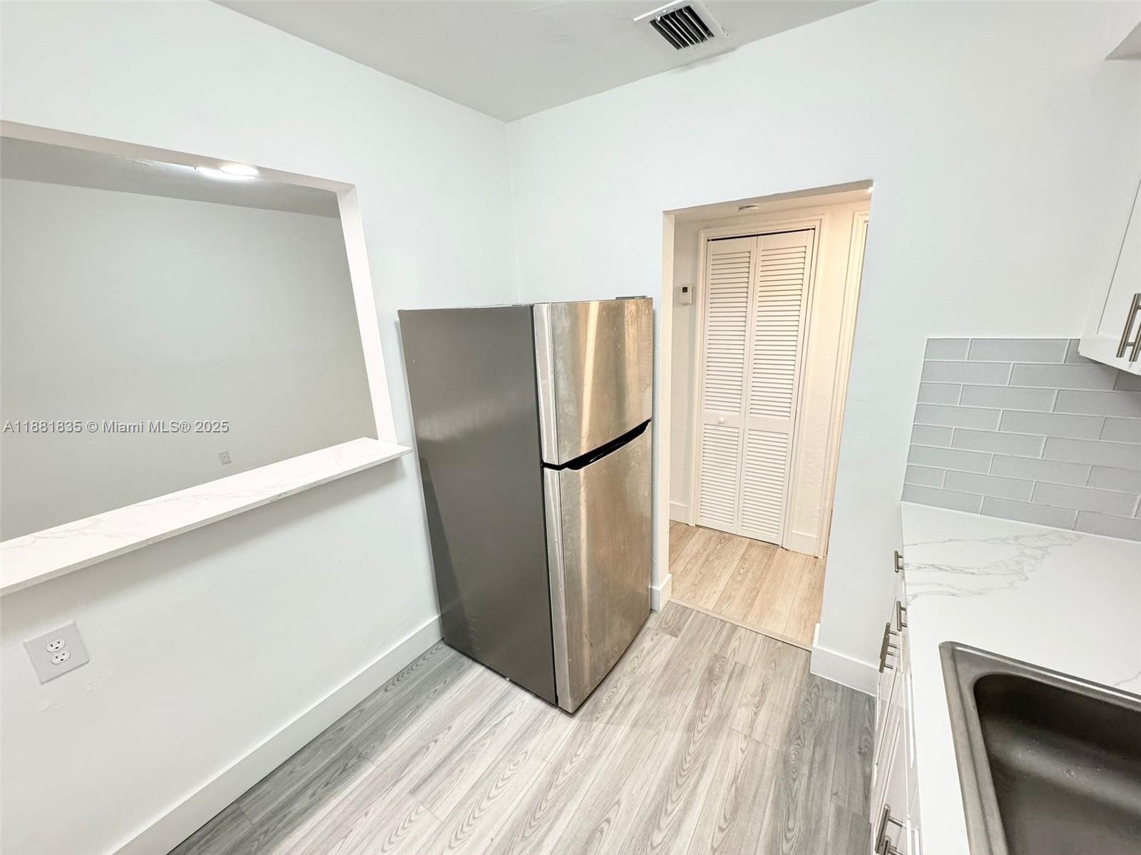 7435 Byron Avenue, Unit 2 Miami Beach, FL 33141 - Photo 5 of 35 a view of a kitchen with refrigerator stove and wooden floor