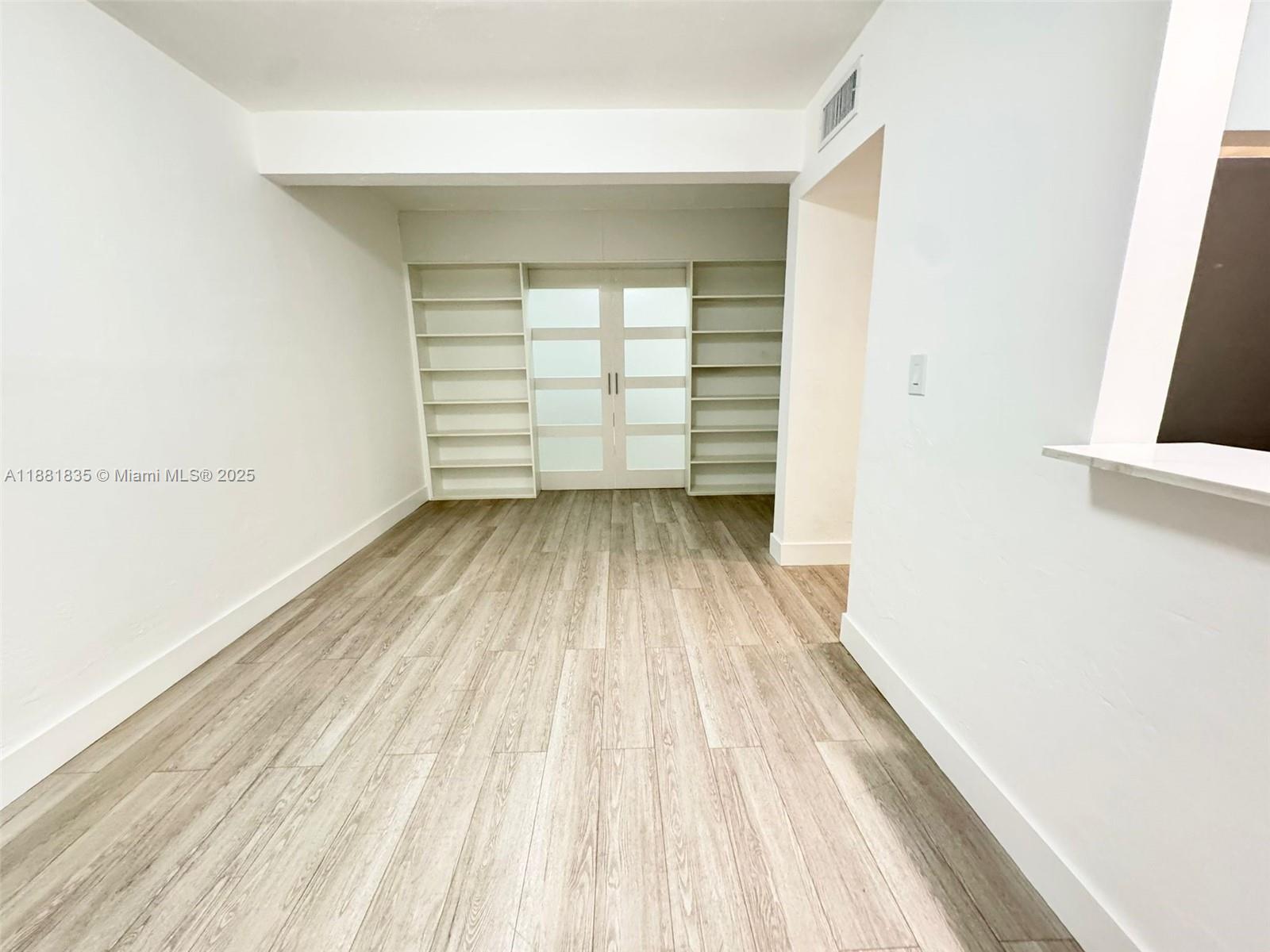 7435 Byron Avenue, Unit 2 Miami Beach, FL 33141 - Photo 8 of 35 a view of a room with wooden floor and white walls