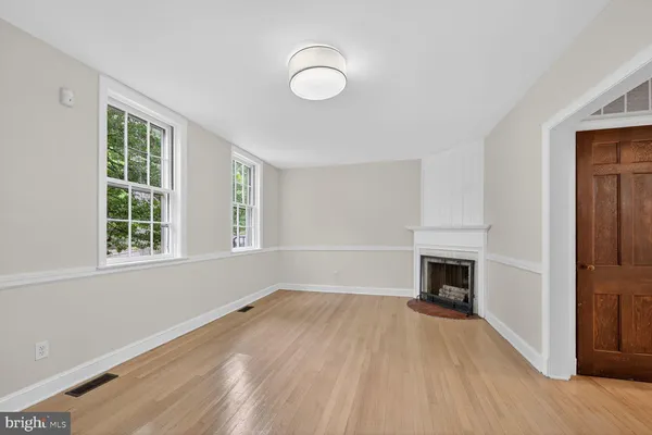 an empty room with windows fireplace and wooden floor