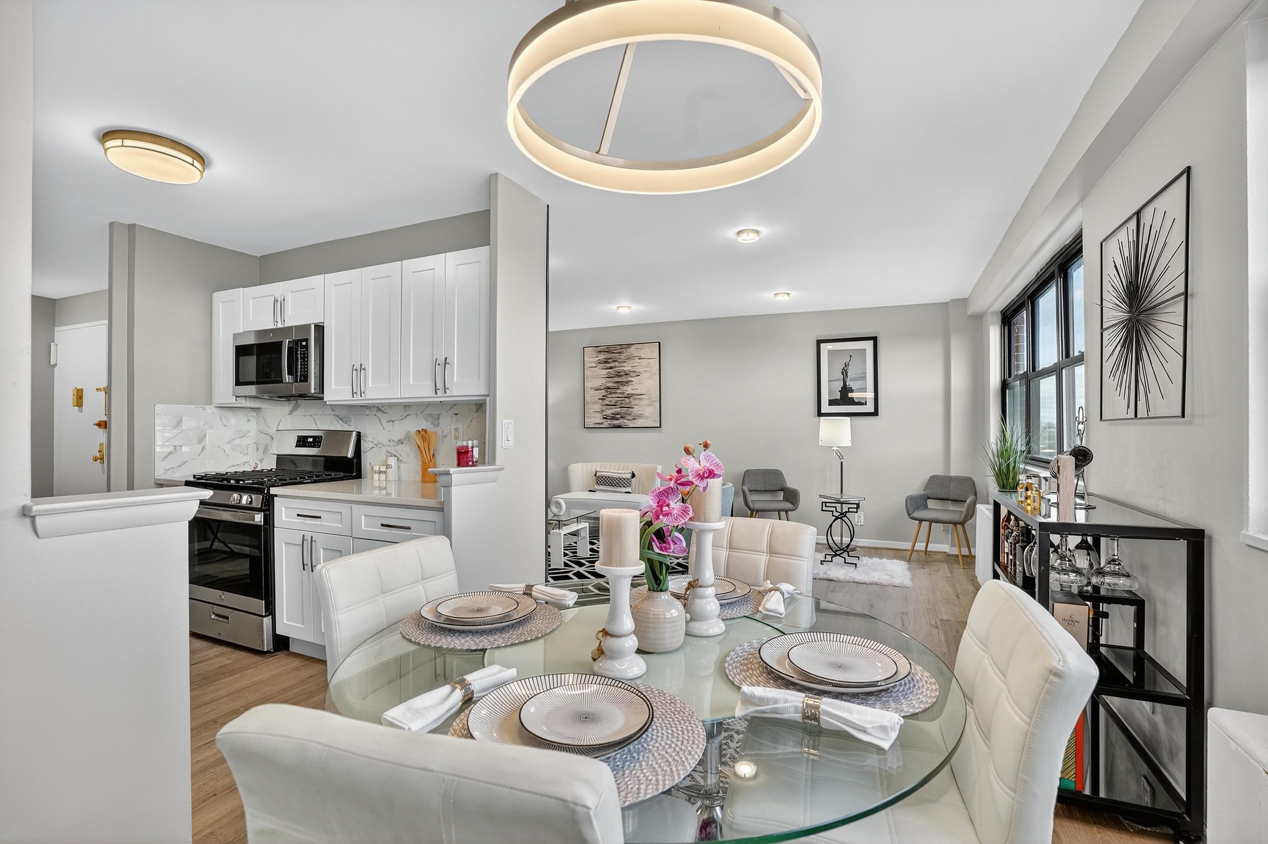 1225 John F. Kennedy Boulevard, Unit 12K Bayonne, NJ 07002 - Photo 13 of 18 a kitchen with stainless steel appliances kitchen island granite countertop a kitchen island a stove a dining table and chairs
