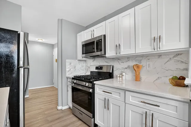 a kitchen with cabinets stainless steel appliances and a wooden floor