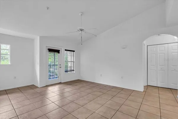 a view of an empty room with window and chandelier fan