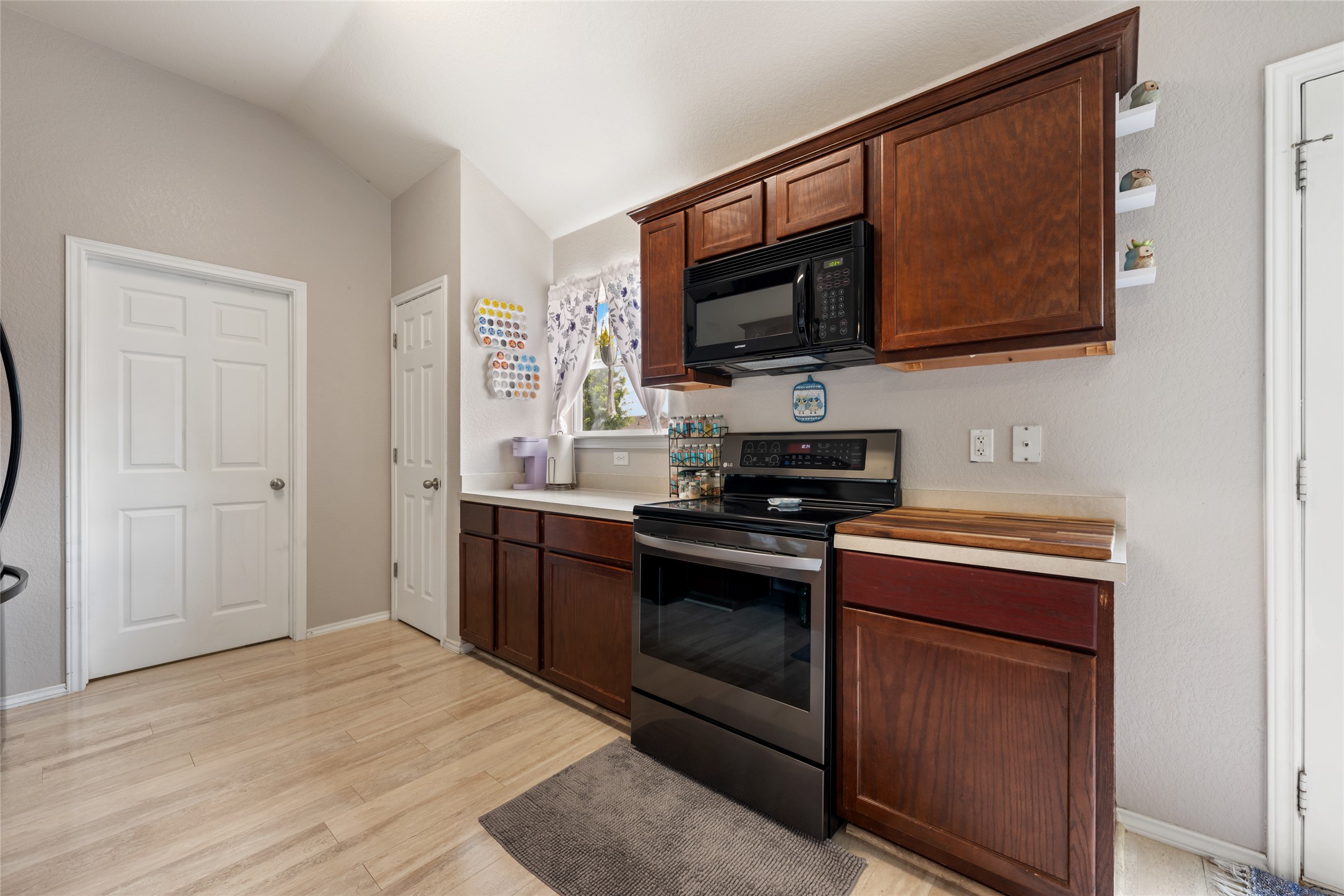 144 Calcite Lane Jarrell, TX 76537 - Photo 15 of 38 Prepare culinary creations in a well-equipped kitchen featuring vaulted ceilings and light wood-style flooring.