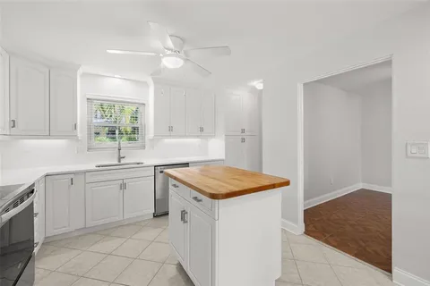 a kitchen with a sink dishwasher a stove and white cabinets