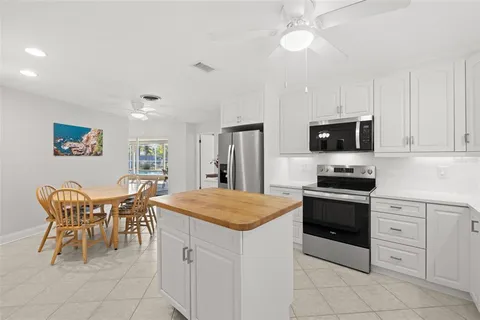 a kitchen with stainless steel appliances kitchen island granite countertop a stove a sink a dining table and chairs