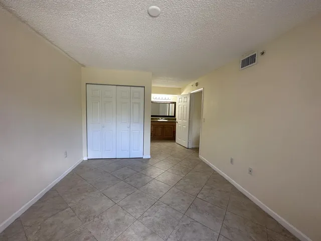 a view of an empty room and a kitchen